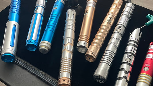 Collection of custom lightsaber hilts on a black stand in a workshop setting
