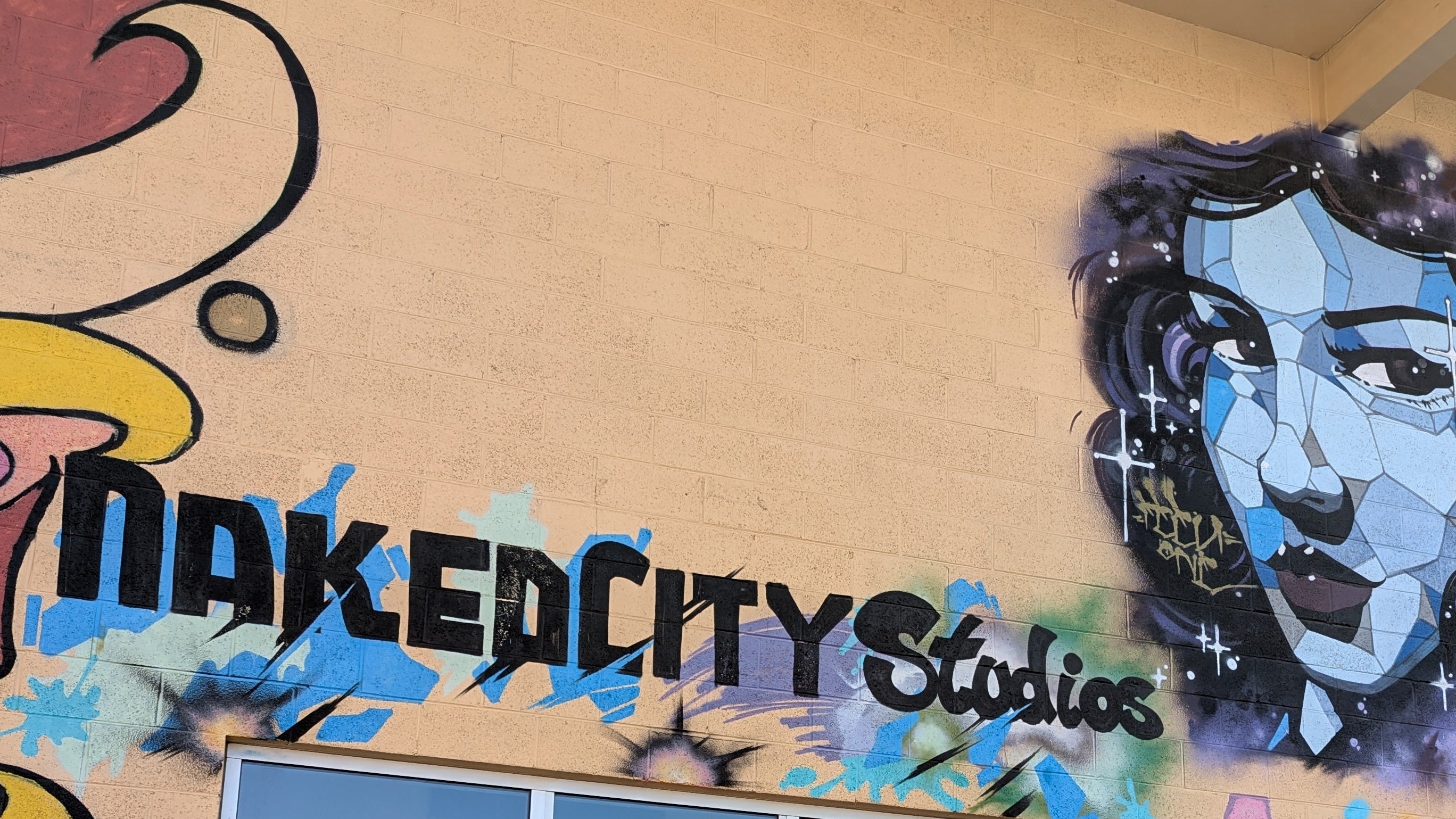 702 Sabers Store front with 'Naked City Studios' and artistic designs.